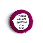 'Please ask one question at a time' pin badge with burgundy background